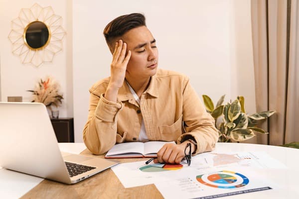 Man appearing stressed while holding head, symbolizing the need for stress management techniques for tinnitus relief.